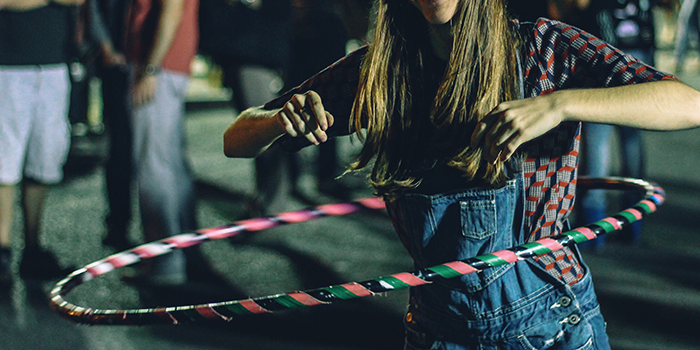 Girl wearing overalls with a black,pink,green striped hula hoop
