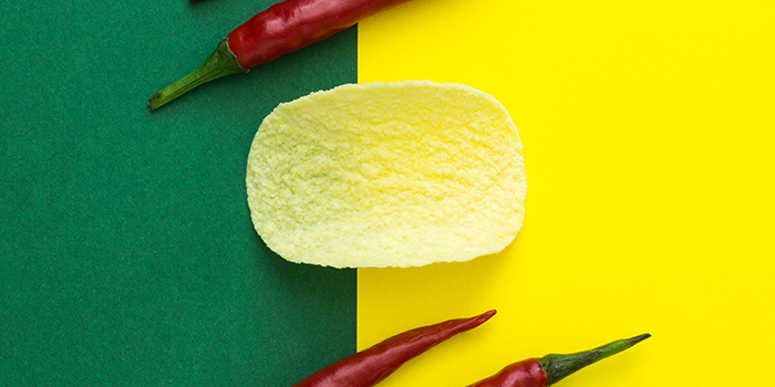 Green and yellow background with chili peppers and a potato chip