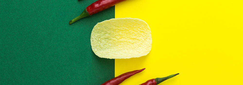 Green and yellow background with chili peppers and a potato chip