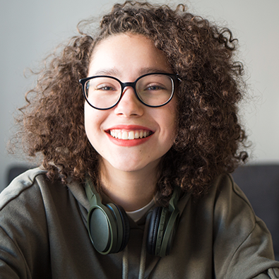 Young woman with curly hair with glasses and headphones around her neck